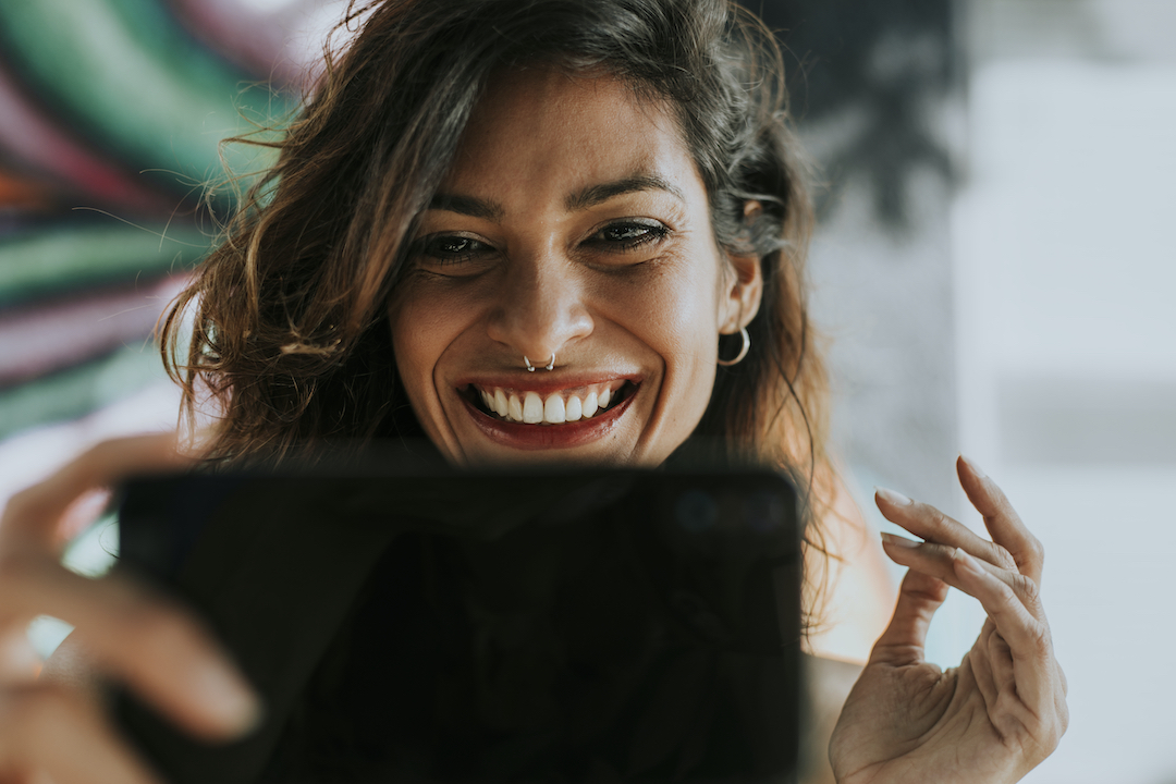 mujer joven sonríe mientras mira la pantalla de su tablet